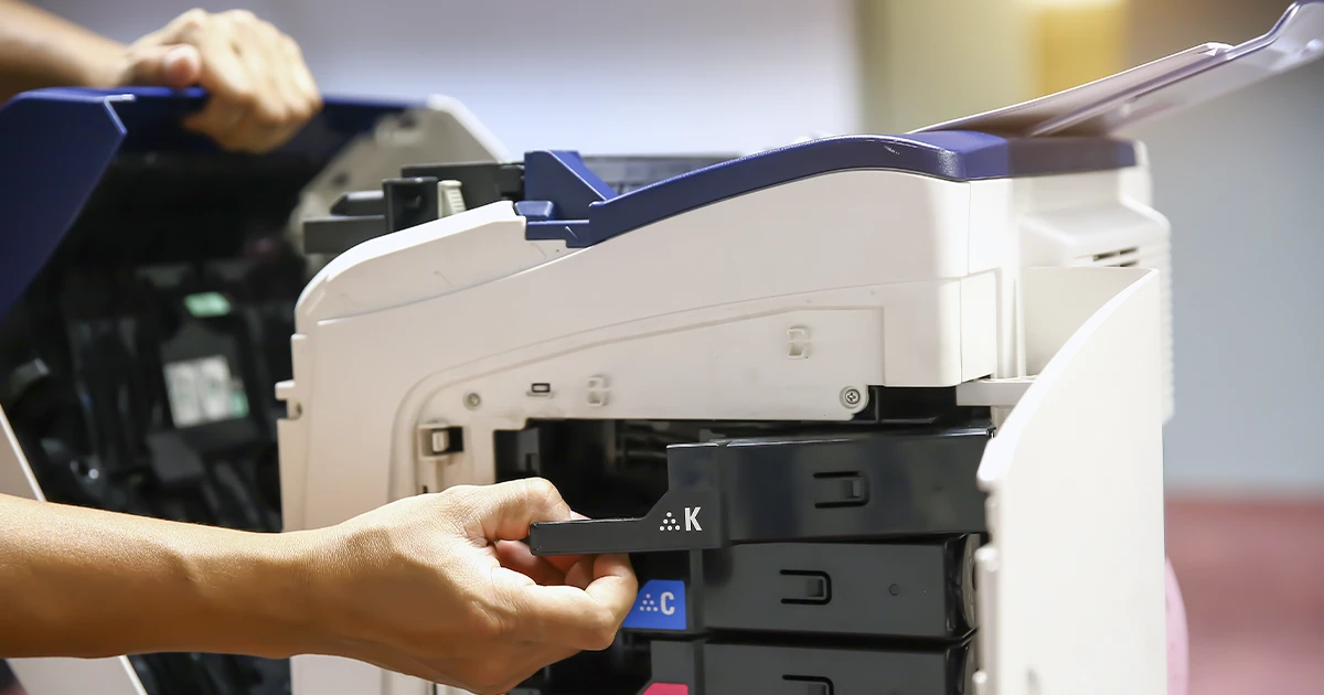 tecnico reparando y retirando los cartuchos de una fotocopiadora blanca con azul